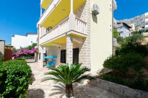 a building with a palm tree in front of it at Apartment Jele in Omiš