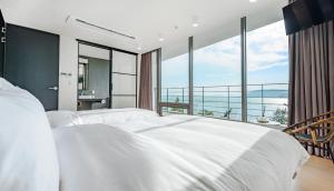 ein Schlafzimmer mit einem großen weißen Bett und einem großen Fenster in der Unterkunft Vigo Resort in Yeosu
