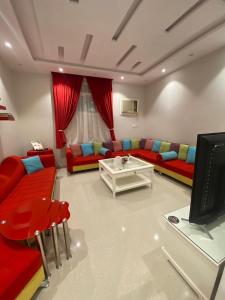 a living room with red couches and a tv at شقة الأصيل سكن خاص بيوت ضيافة غرفة وصالة مستقلة لا يوجد مصعد درج فقط Al Aseel Apartment Buyoot Al Diyafah in Taif