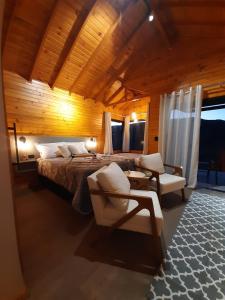 um quarto com uma cama e cadeiras num quarto em Pousada Recanto da Cascata - Cabana Platano em São Joaquim