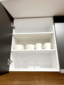 a white cabinet with cups and glasses on it at Moschato New Home 3 vipgreece in Piraeus