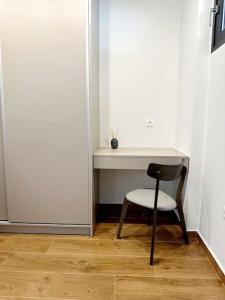 einen Schreibtisch mit einem Stuhl neben einer weißen Wand in der Unterkunft Moschato New Home 3 vipgreece in Piräus