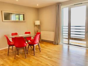 Stunning 3 bed seaview apartment في ماسلبرغ: غرفة طعام مع كراسي حمراء وطاولة