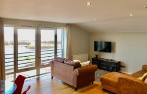 a living room with a couch and a television at Stunning 3 bed seaview apartment in Musselburgh