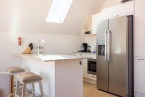 a white kitchen with a stainless steel refrigerator at Downtown Dreamstay, Classic 2BR Suites in Willemstad +44 photos