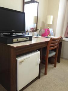 a desk with a television and a small refrigerator at Sky Heart Hotel Kawasaki in Kawasaki