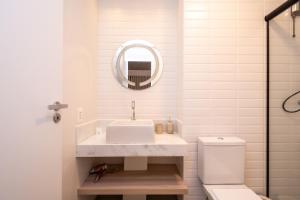 a white bathroom with a sink and a mirror at Lindos apto com piscina no Setor Oeste IDV in Goiânia
