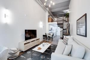 a living room with a white couch and a tv at The Ledger Residences by Sosuite - Old City in Philadelphia