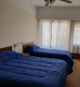 um quarto com 2 camas azuis e uma janela em Nueva Hostería Rio Colorado Necochea em Necochea