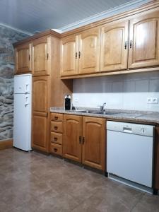 eine Küche mit Holzschränken und weißen Geräten in der Unterkunft ROSAS DA GRANJA - CASA DE CAMPO in Granja
