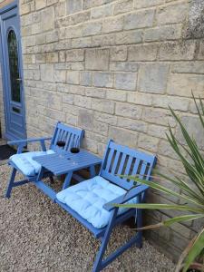 two blue chairs and a table next to a brick wall at The Old Bar in Wiltshire - 1 bedroom guesthouse in Chippenham