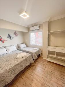 a bedroom with two beds and a window at Brisa Mar Apartamento Aconchego in Balneário Camboriú