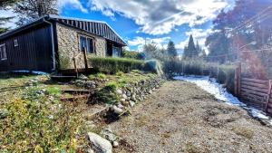 una pequeña casa con una pared de piedra junto a un río en Llanten del Trébol en San Carlos de Bariloche