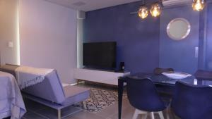 ein Wohnzimmer mit einem TV, einem Tisch und Stühlen in der Unterkunft Paraiso Paulista Premium in São Paulo
