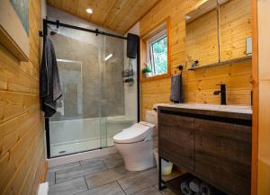 a bathroom with a toilet and a shower and a sink at 1-bedroom knotty Pine cabin w sauna & jacuzzi in Sooke