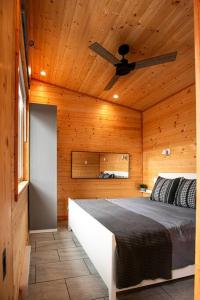 1 dormitorio con 1 cama y ventilador de techo en 1-bedroom knotty Pine cabin w sauna & jacuzzi, en Sooke