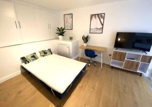 Habitación con cama, escritorio y TV. en Redhill Town Centre Garden Flat en Redhill