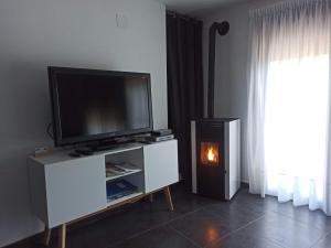 sala de estar con TV de pantalla plana y chimenea en Casa rural La Senyora, en Veo