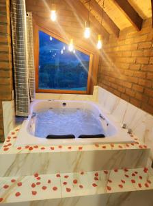 a large bath tub in a room with a window at Pousada das Castanheiras in Monte Verde