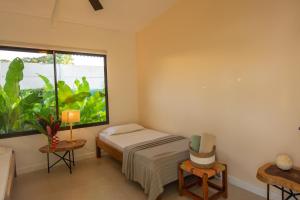 um quarto com uma cama e uma grande janela em Namaitamí Casa Hermosa con AC y piscina a Solo 650 Metros del Parque Nacional Cahuita em Cahuita