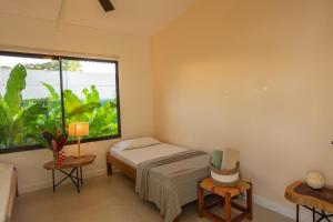 - une chambre avec un lit et une grande fenêtre dans l'établissement Namaitamí Casa Hermosa con AC y piscina a Solo 650 Metros del Parque Nacional Cahuita, à Cahuita