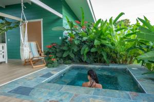uma mulher sentada numa piscina ao lado de uma casa em Namaitamí Casa Hermosa con AC y piscina a Solo 650 Metros del Parque Nacional Cahuita em Cahuita