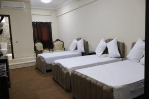 um quarto de hotel com duas camas com lençóis brancos em رويال ماجيك no Cairo