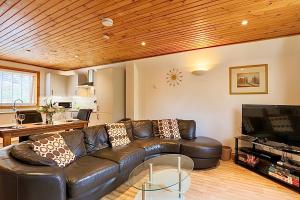 a living room with a leather couch and a table at Retreat to Oak Tree Lodge - A Romantic Getaway in Devon's Finlake Resort & Spa in Chudleigh