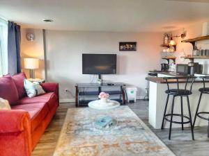 a living room with a red couch and a kitchen at Cozy Private Suite in Winnipeg