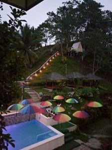 a group of colorful umbrellas next to a swimming pool at JKO woodland resort in Malampay