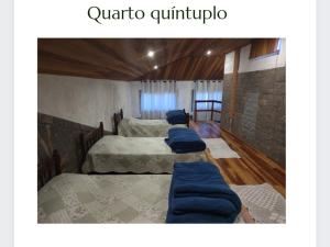 a room with three beds with blue pillows on them at Flats Brancas Nuvens in Campos do Jordão