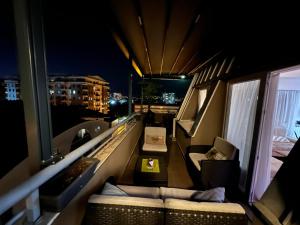 Cette chambre dispose d'un balcon avec un canapé et des chaises. dans l'établissement Lusso Apartment, à Skopje