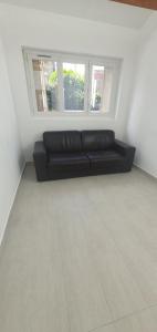 a black couch in a room with two windows at Le 23 in Colombes