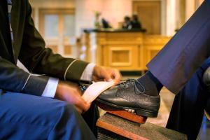 two men in suits are tying their shoes at Hilton Sandton in Johannesburg
