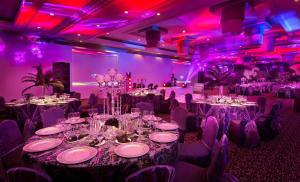 a room filled with tables and chairs with purple lights at NH Johannesburg Sandton in Johannesburg +46 photos