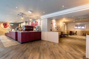 a restaurant with a counter and tables and chairs at Hilton London Olympia in London