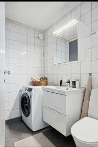 a white bathroom with a washing machine and a sink at Rekkehus i Trondheim, gratis parkering in Trondheim