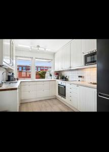 a large white kitchen with white cabinets and windows at Rekkehus i Trondheim, gratis parkering in Trondheim