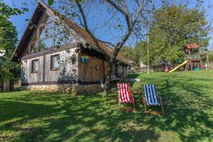 two chairs sitting in the grass in front of a house at Hedgehog's Home in Korenica