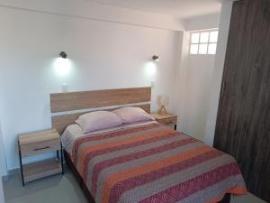 ein Schlafzimmer mit einem Bett mit einer gestreiften Decke und zwei Nachttischen in der Unterkunft II - Zaguan Aparta Hotel Cusco in Cusco