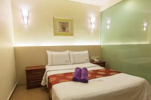a hotel room with a bed with purple shoes on it at Lavender Inn Permas Jaya in Johor Bahru
