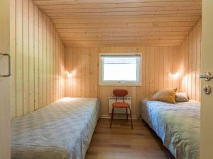 2 Betten in einem Zimmer mit einem Fenster und einem Stuhl in der Unterkunft Holiday home Nørre Nebel III in Nørre Nebel