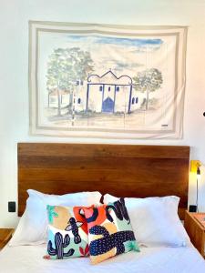 ein Gemälde über einem Bett mit zwei Kissen darauf in der Unterkunft XIQUE XIQUE ITAUNAS HOSPEDARIA in Itaúnas