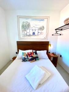 ein Schlafzimmer mit einem weißen Bett mit einem Bild an der Wand in der Unterkunft XIQUE XIQUE ITAUNAS HOSPEDARIA in Itaúnas