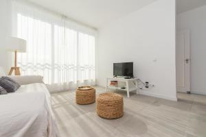 a white bedroom with a bed and a tv at Casa do Ser in Fuzeta