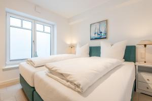 two beds in a white room with a window at Haus Dünenweg Whg 2 in Hörnum