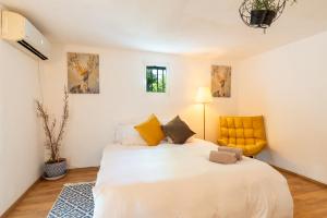 ein Schlafzimmer mit einem weißen Bett und einem gelben Stuhl in der Unterkunft Perfect Apartment Jaffa Beach in Tel Aviv