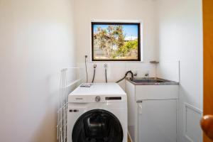 - une buanderie avec un lave-linge et un évier dans l'établissement Lakeside Stunner - Omori Holiday Home, à Kuratau