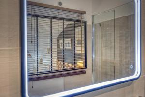 - un miroir dans la salle de bains avec une fenêtre et des stores dans l'établissement Le Loft 39 - CHU, à La Tronche