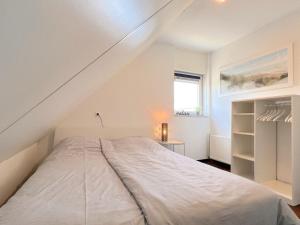 ein weißes Schlafzimmer mit einem Bett und einem Fenster in der Unterkunft Sonnenschein in Stevensweert
